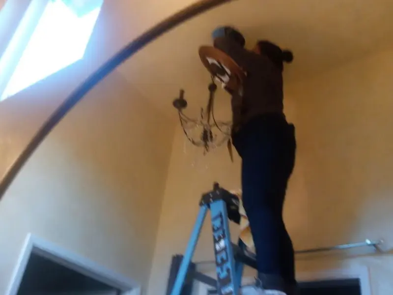 Electrician installing a chandelier in a Laurens residence